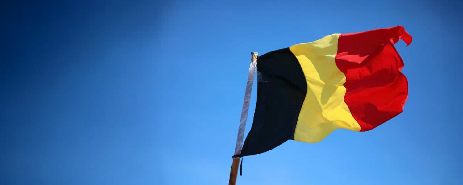 Photo of the Belgian flag flying in a blue sky. Used as a header image for the blog titled "Everything you need to know about the Belgium eInvoicing mandate"