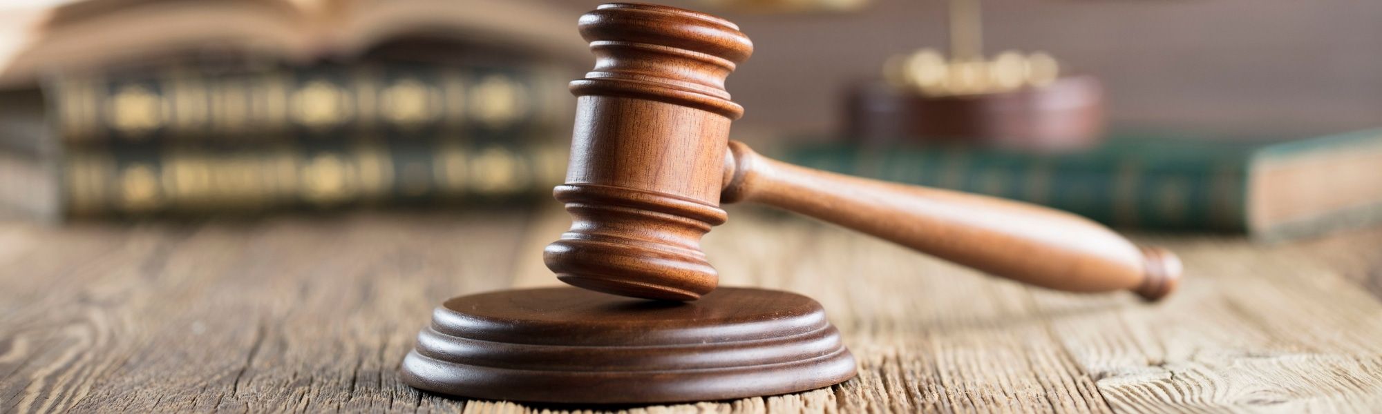 Close up of wooden desk with gavel in foreground and legal texts and scales in blurred background. Representing blog titled "Ensuring tax governance during business territory expansion"