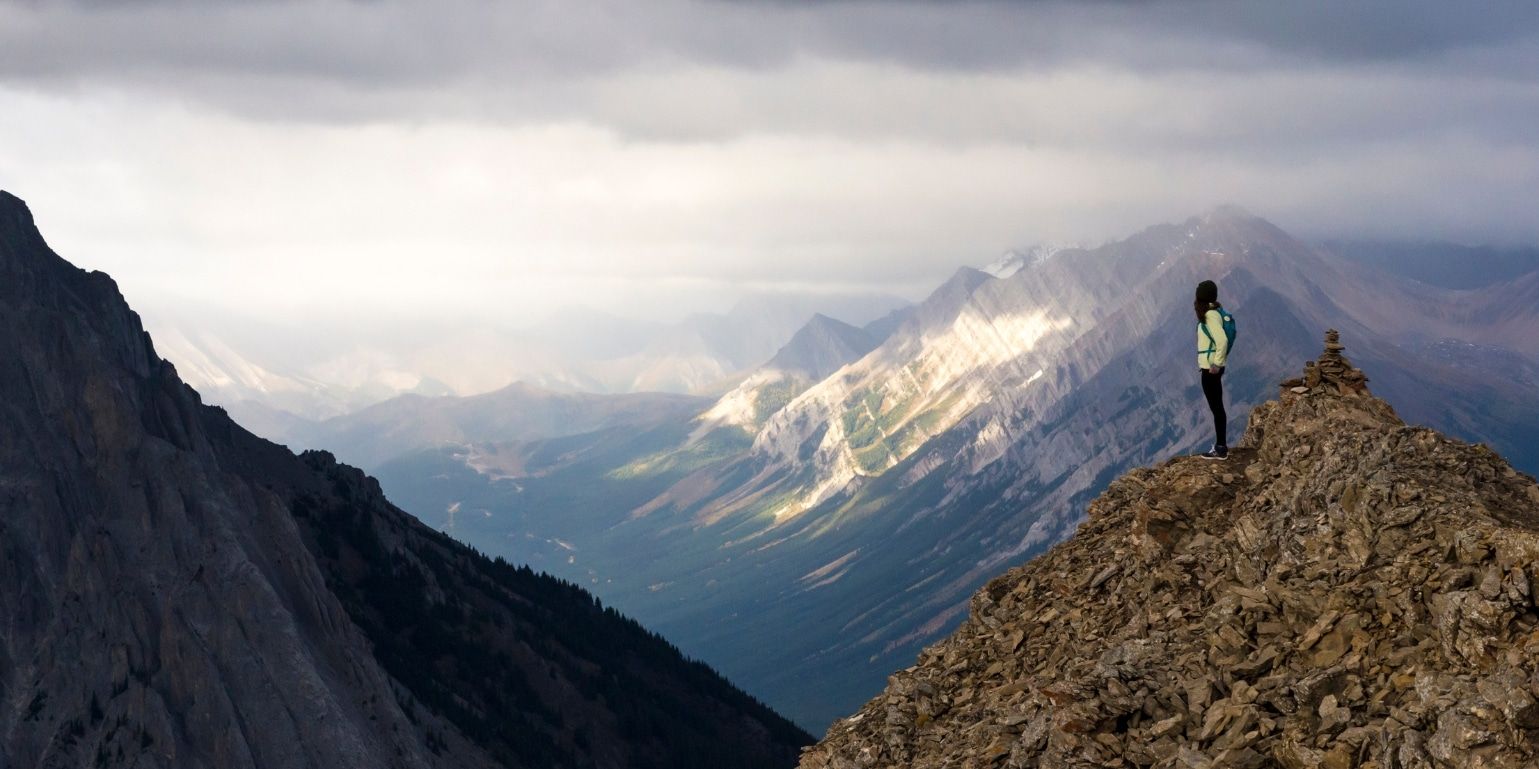Hiker atop mountain overlooking view. Supply chain integration for increased visibility