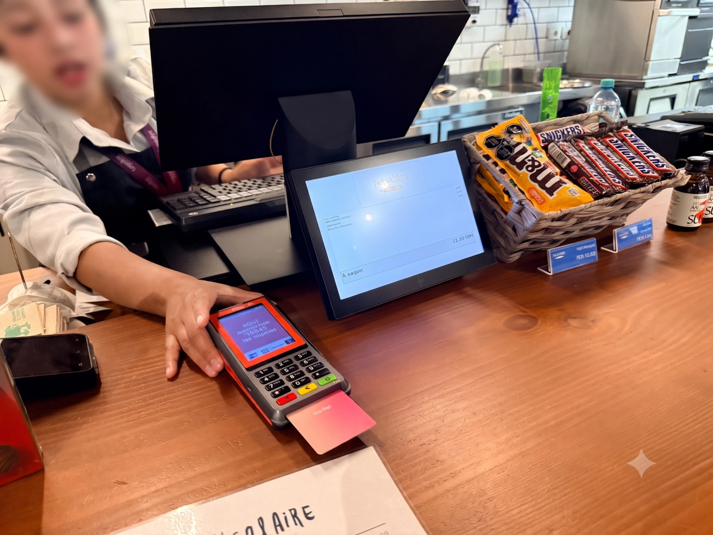 페루 매장 계산대에서 직원이 카드가 삽입된 결제 단말기를 조작하고 있고, 옆 진열대 가격표에 PEN 단위 금액이 표시된 모습