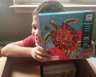 Kid hiding behind art kit.