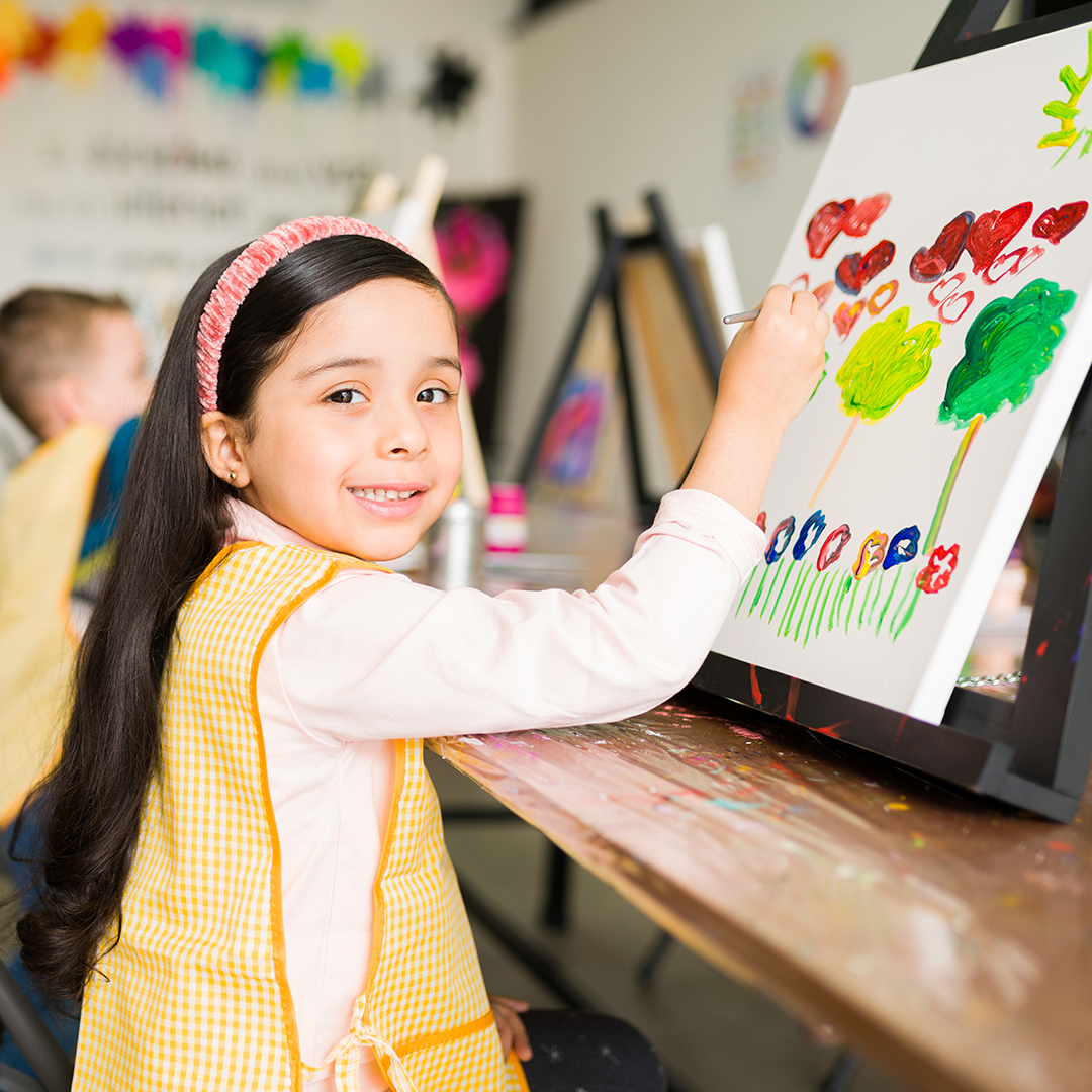 Girl at easel painting a picture.
