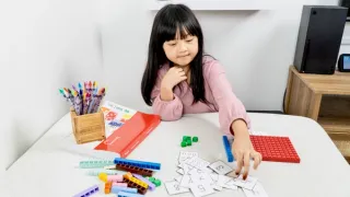 A girl at a table with math blocks and number cards
