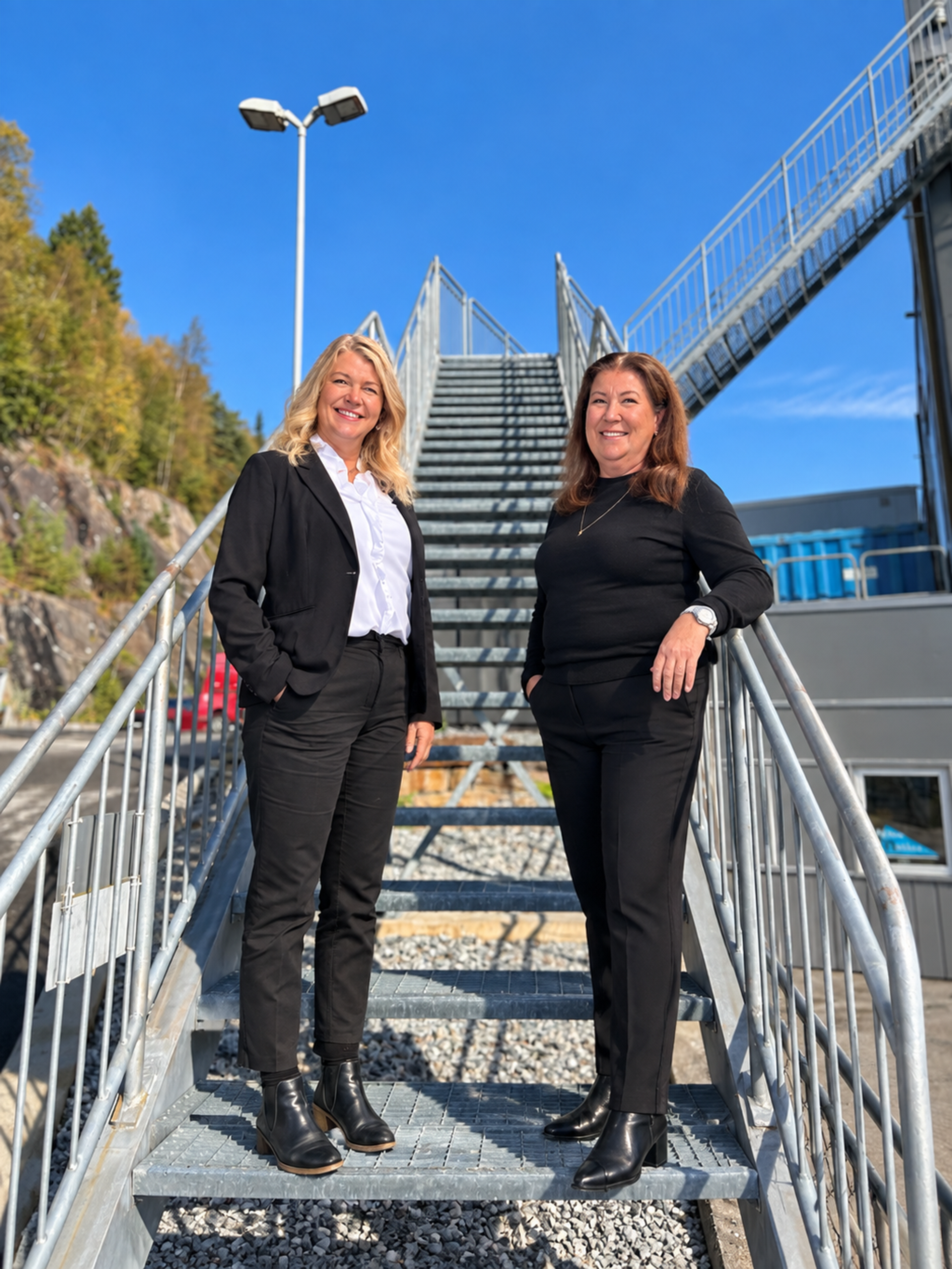 Irene Knutsen og Anita Myking står i en ståltrapp i høstsol