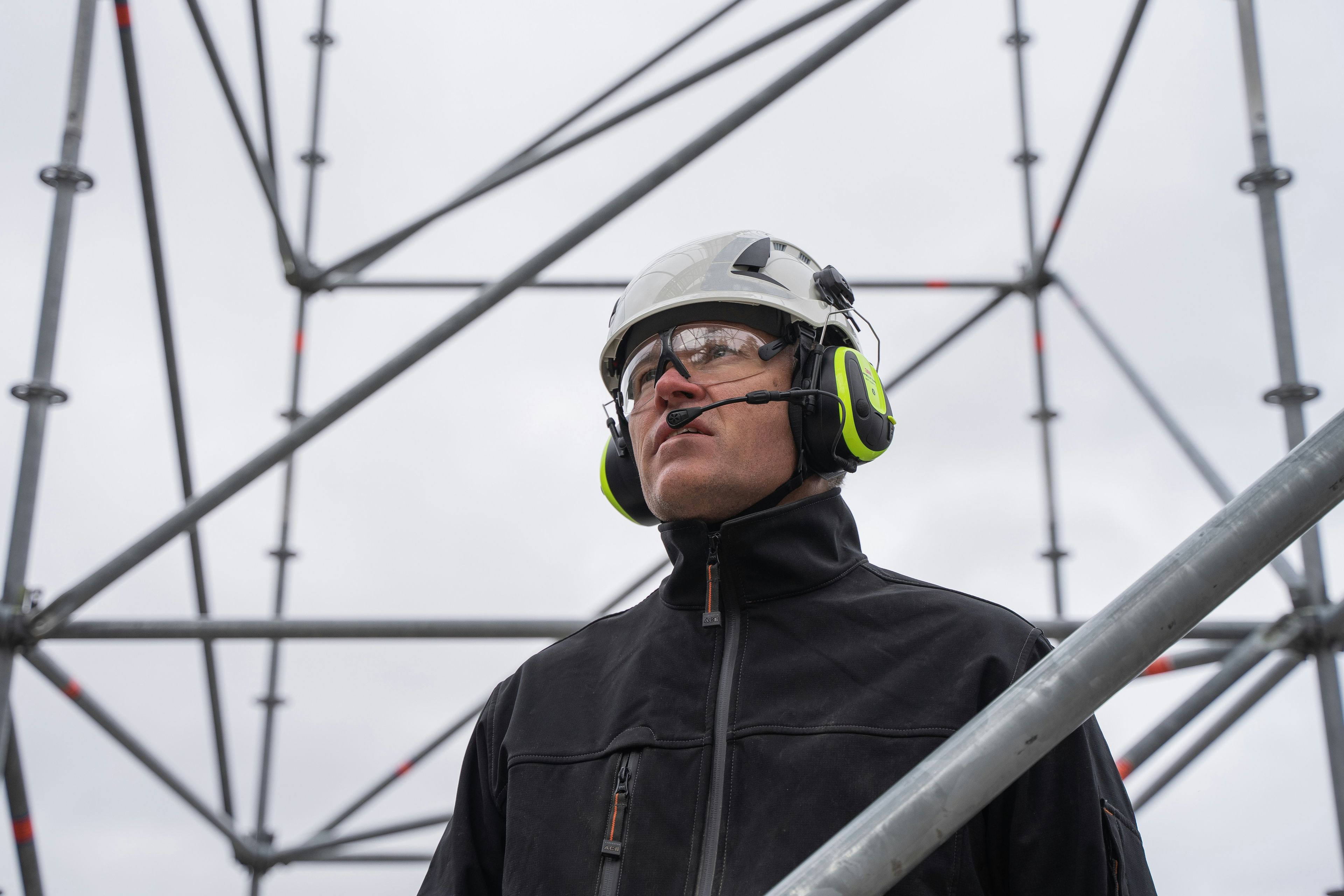 Formann med hjelm og hørselvern under en stålmast