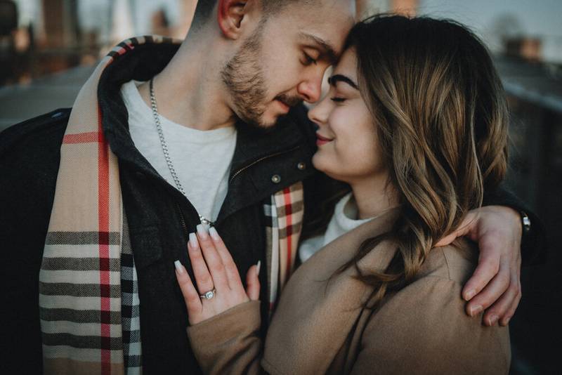 Woman puts hand with engagement ring on boyfriend's chest