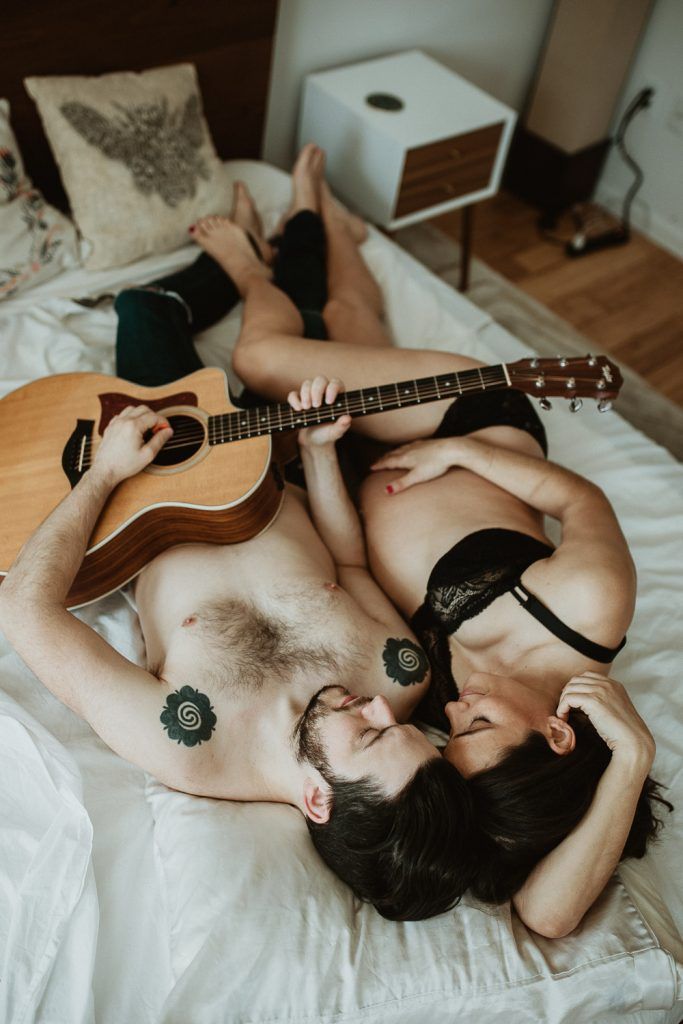 Expecting couple plays guitar in bed during maternity shoot in brooklyn home