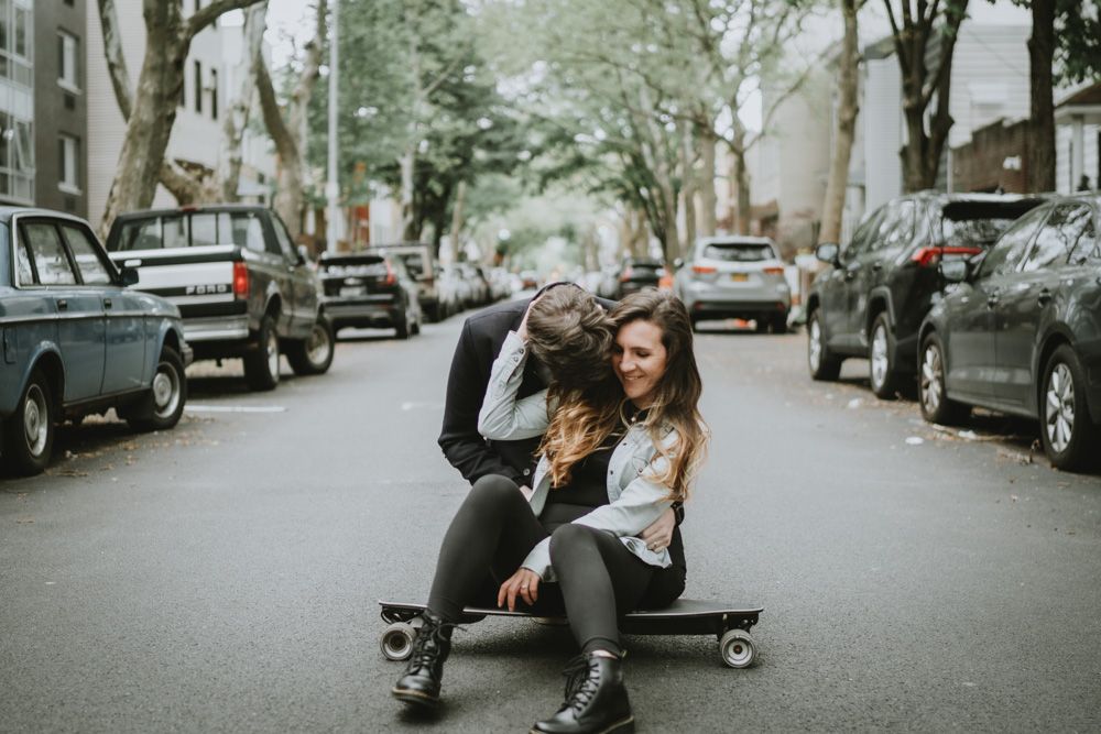 Couple sitting on skateboard in middle of brooklyn street