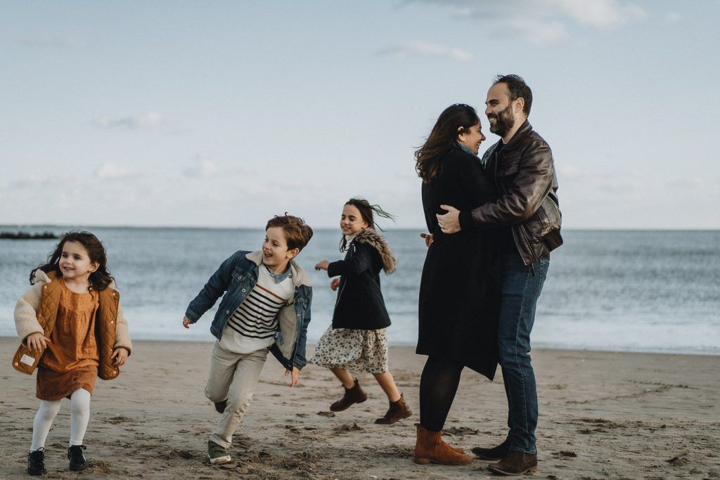 Parents play with three kids during family session at coney island beach