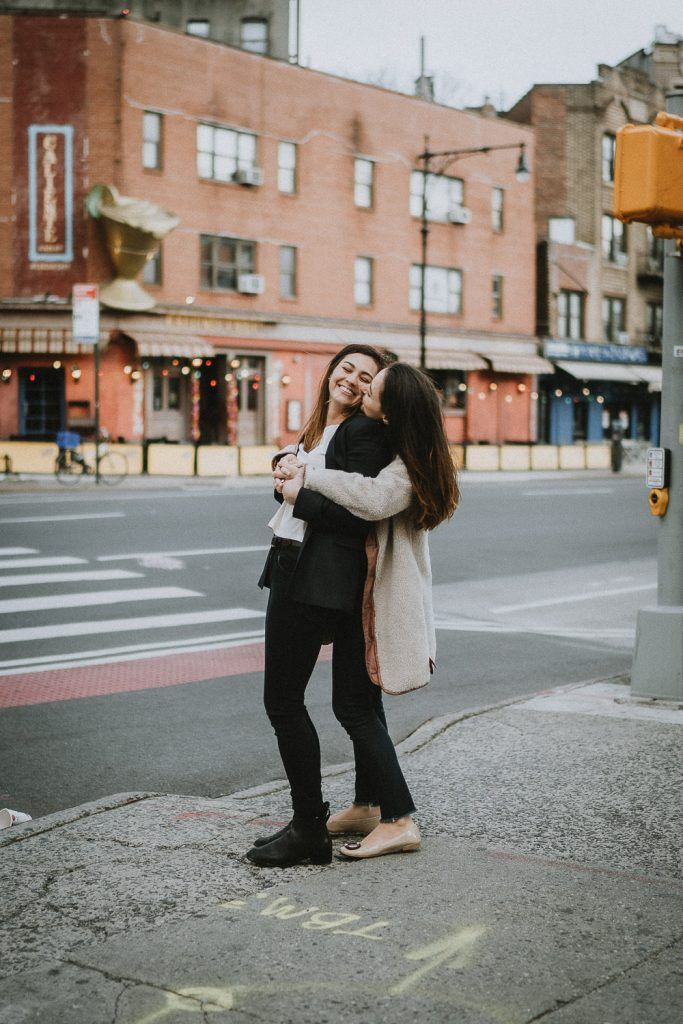 Lesbian couple snuggling in nyc street during engagement session
