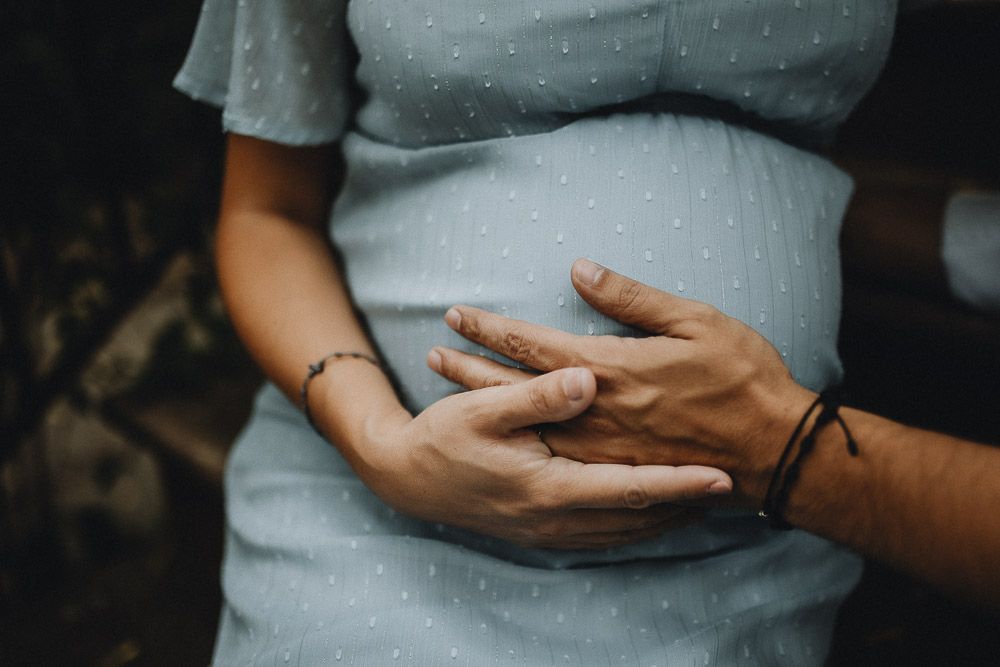 Close up of expecting couple's hands on baby bump