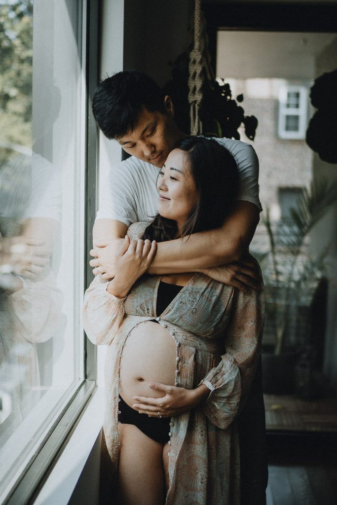 Expecting couple snuggling at home during maternity session in brooklyn