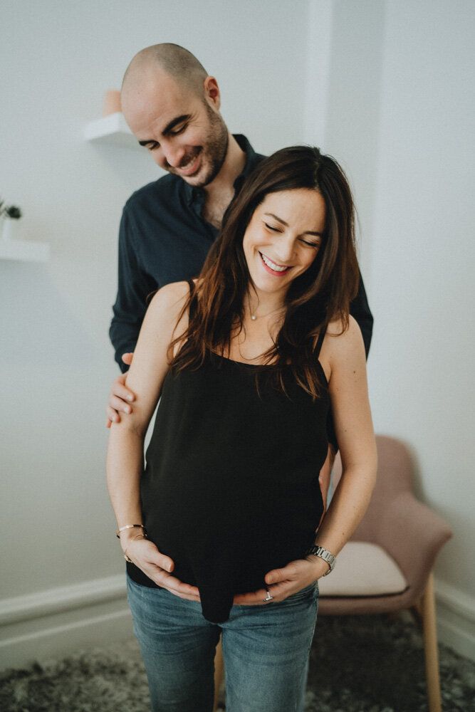 Expecting couple snuggling and laughing during in home maternity session