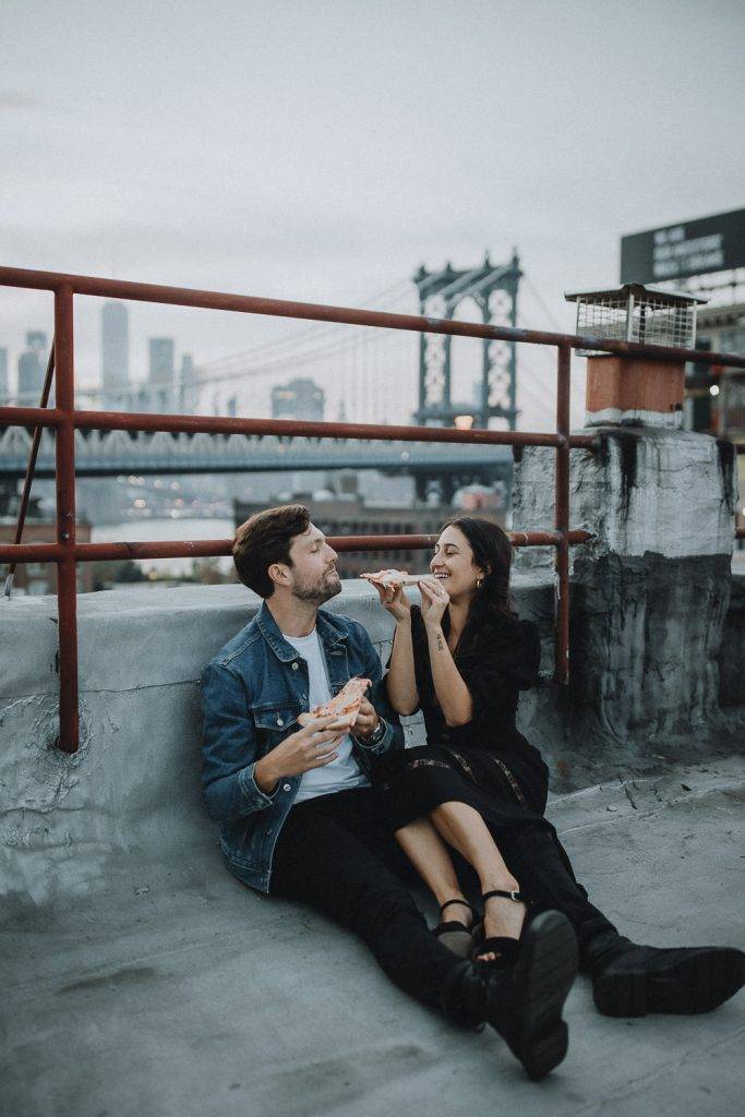 Couple eating pizza during brooklyn rooftop engagement session
