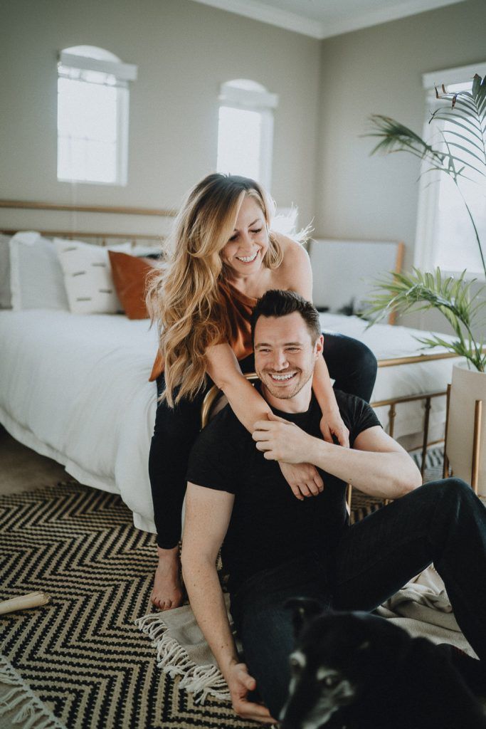 Couple laughs by bed during in home session in brooklyn