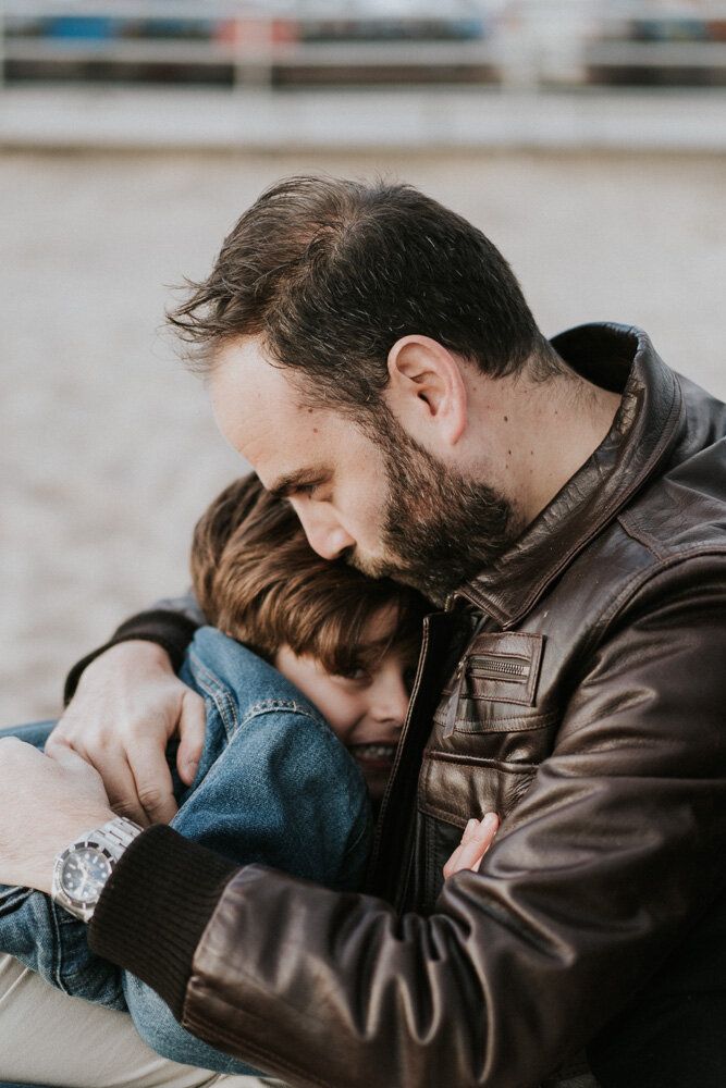 Dad and son snuggle during family session at coney island beach