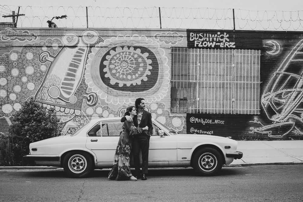 Couple snuggling by old vintage car during brooklyn elopement