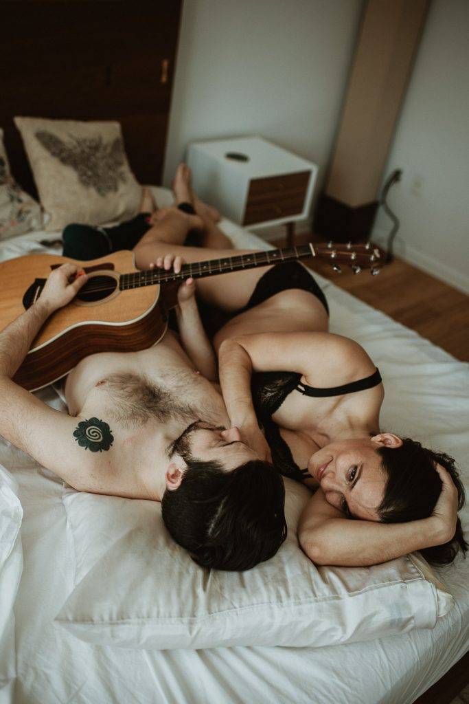 Expecting couple plays guitar in bed during maternity shoot in brooklyn home
