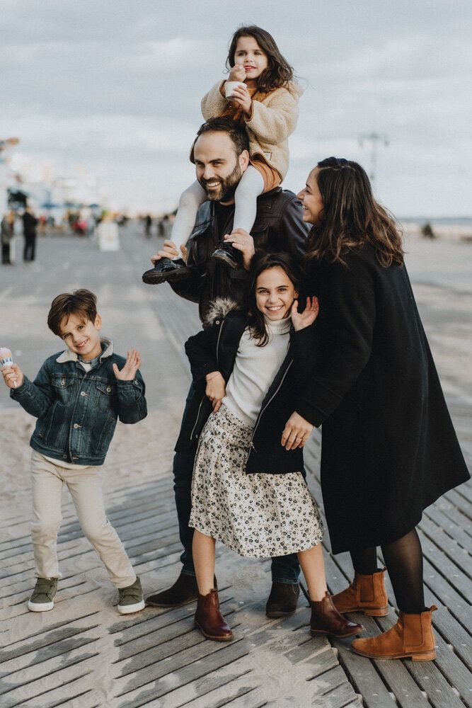 Parents and three kids goofing around during family session at coney island