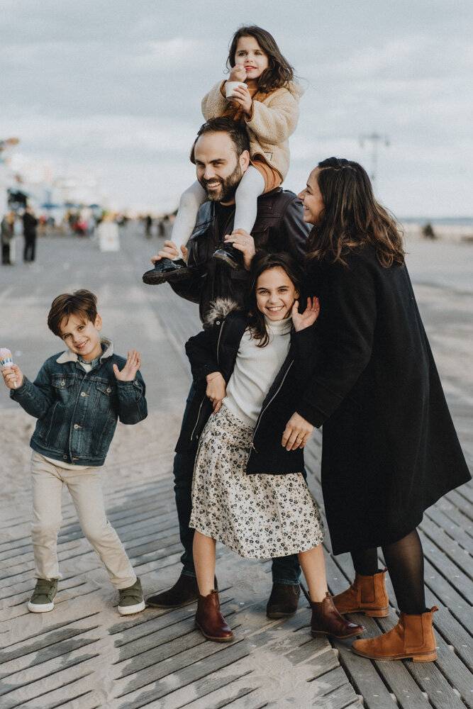 Parents and three kids goofing around during family session at coney island