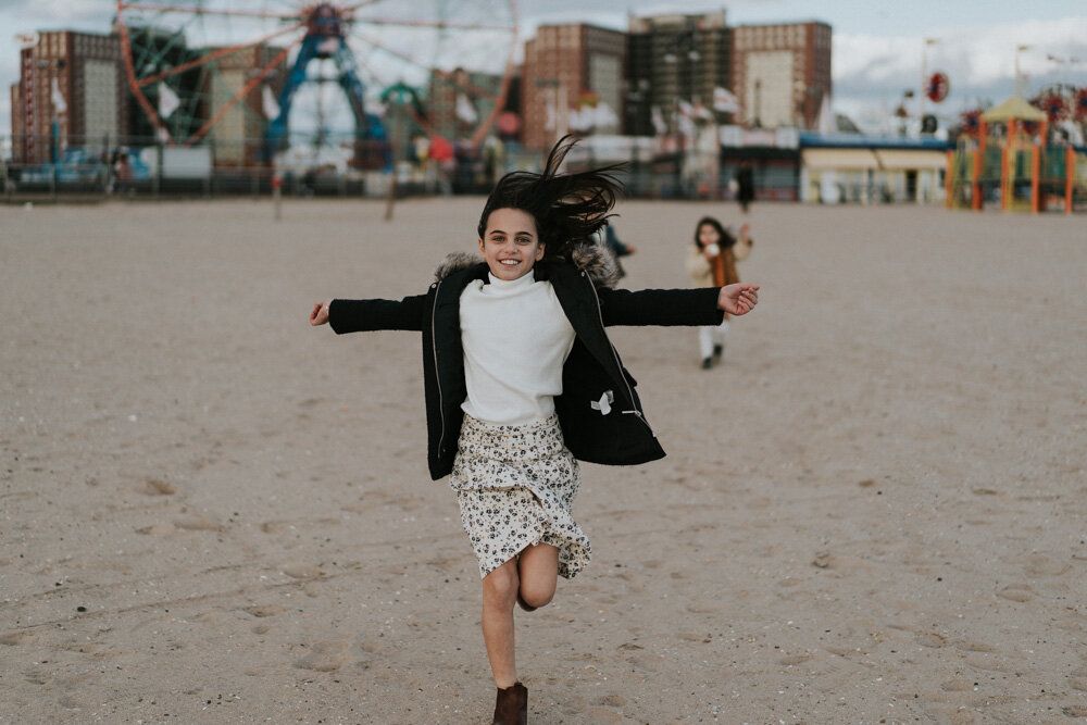 Young girl runs during family session at coney island beach