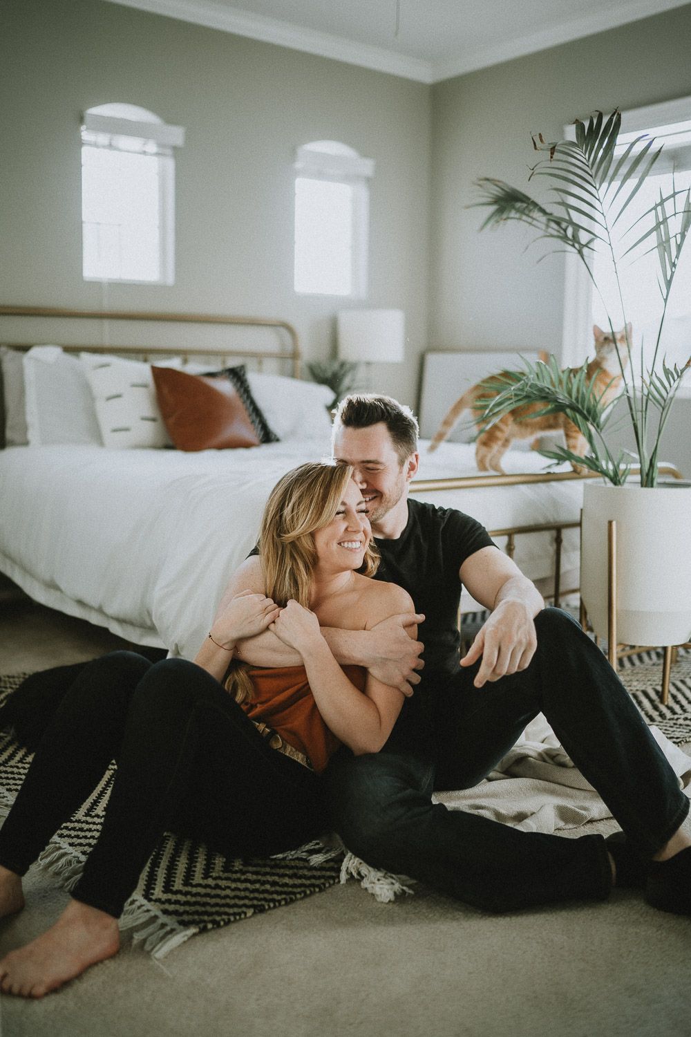 Couple laughs by bed during in home session in brooklyn