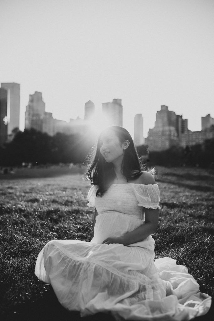 Pregnant woman in central park at golden hour during maternity photoshoot