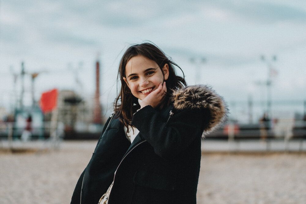 Young girl smiles at photographer during family session at coney island beach