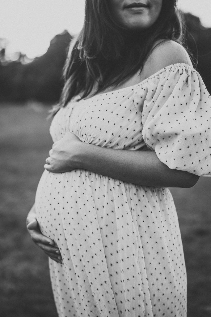 Pregnant woman touching baby bump during maternity session in prospect park