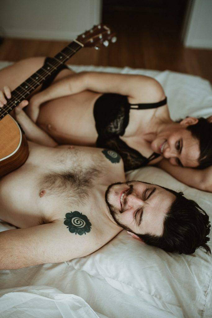 Expecting couple plays guitar in bed during maternity shoot in brooklyn home