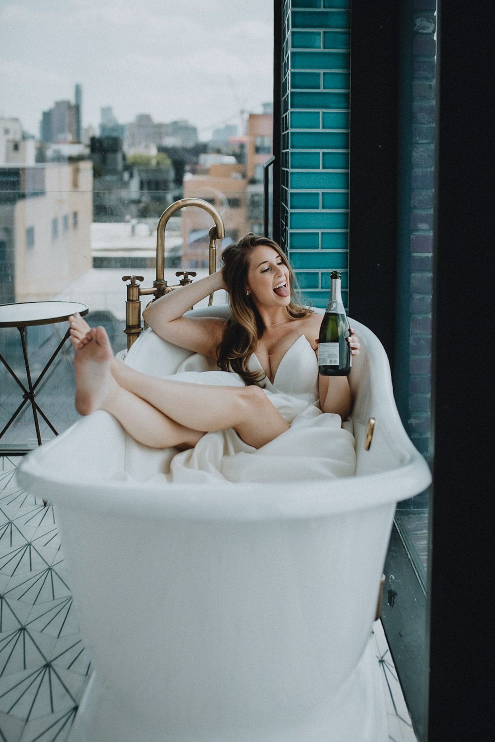 Bride drinking champagne in bathtub at williamsburg hotel
