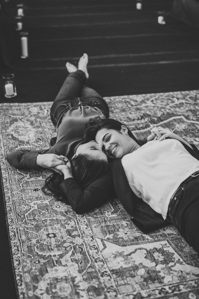 Lesbian couple lying down on rooftop during nyc engagement photoshoot