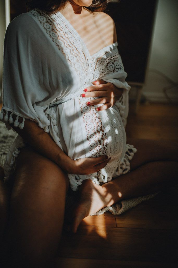Pregnant woman in light and shadows during maternity photoshoot in brooklyn home