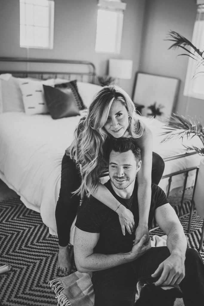Couple cuddles by bed during in home session in brooklyn
