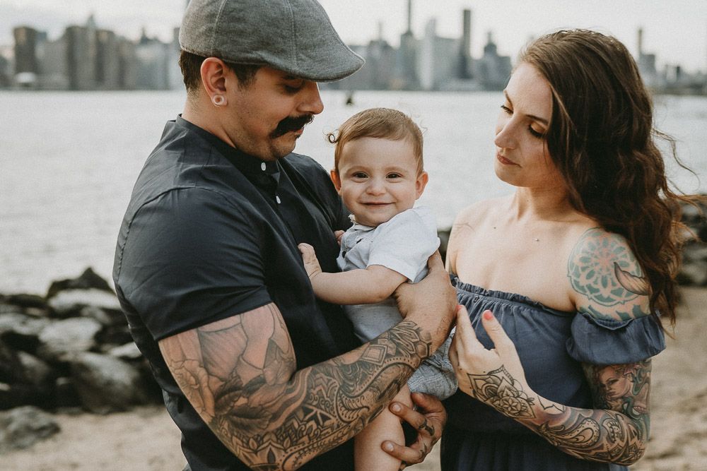 Parents and baby snuggle during family session by the nyc skyline