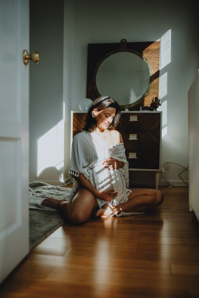 Pregnant woman in light and shadows during maternity photoshoot in brooklyn home