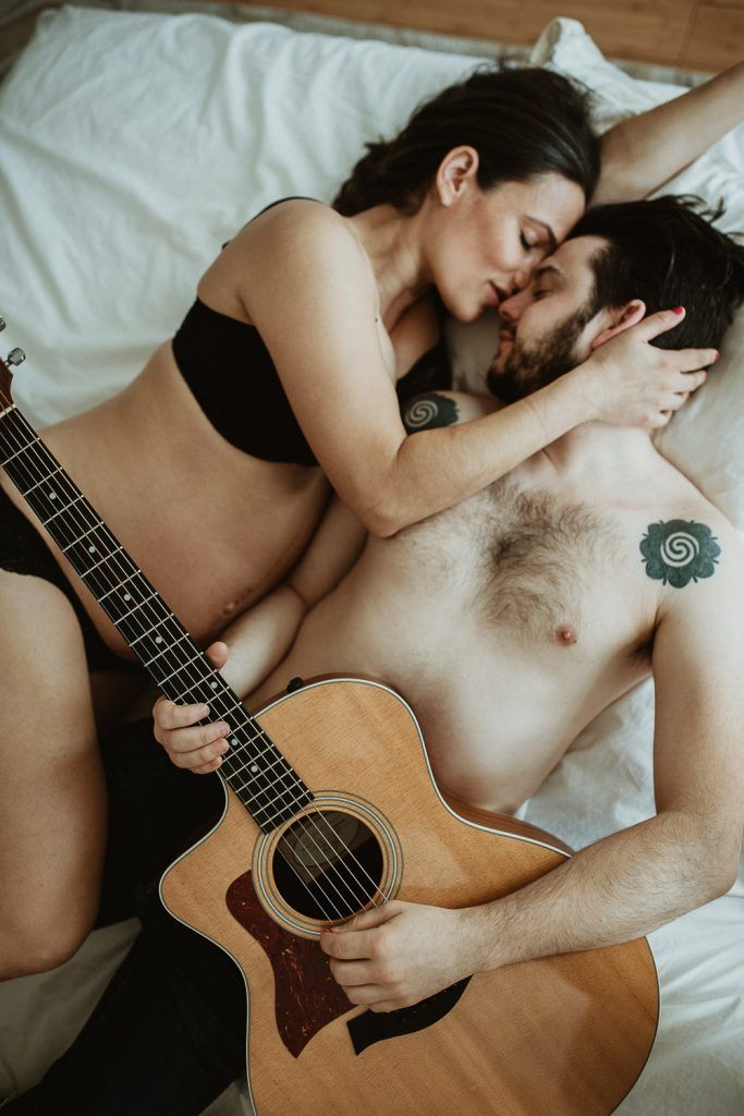 Expecting couple plays guitar in bed during maternity shoot in brooklyn home