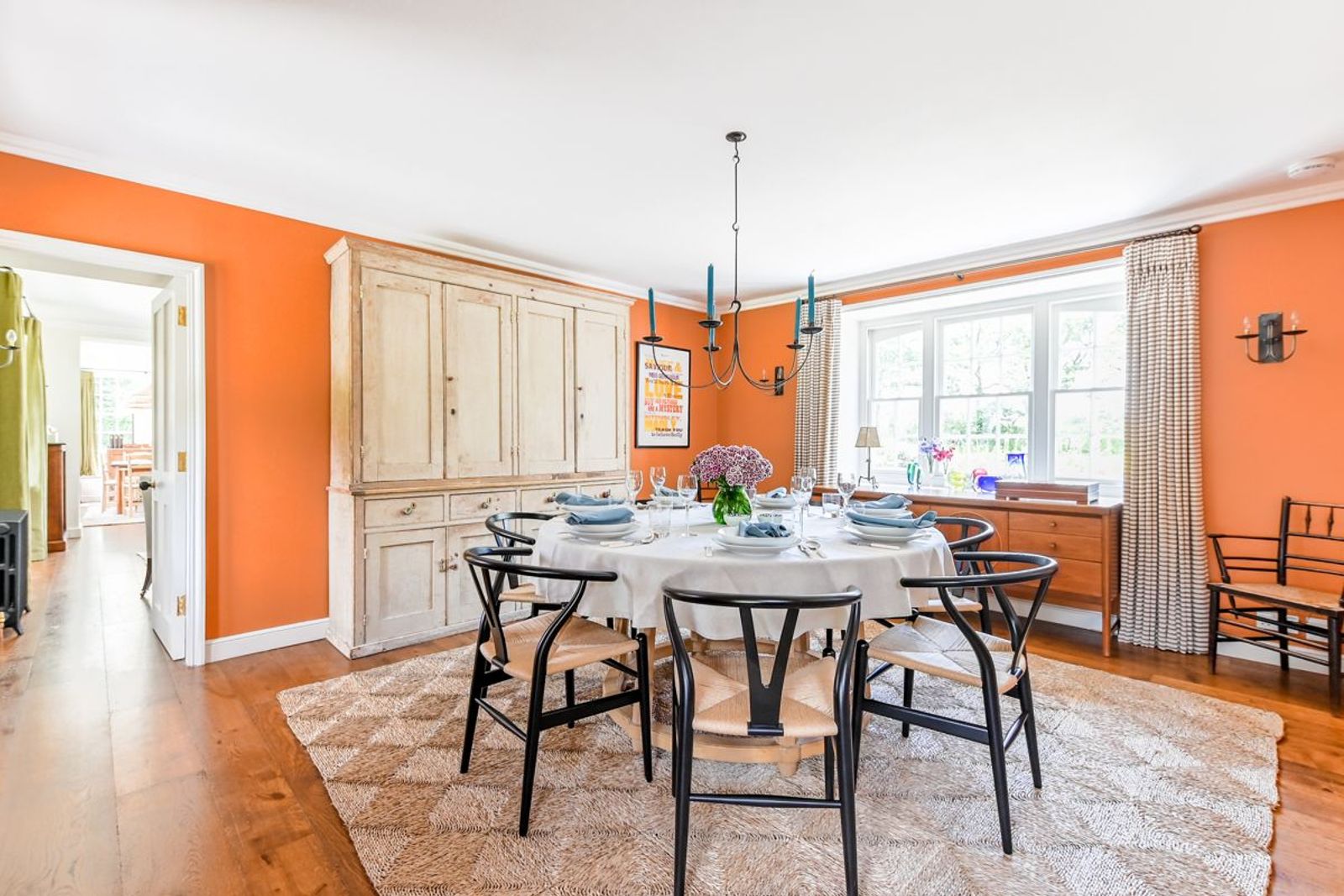 The dining room at Ince Barton, with orange walls and a round table