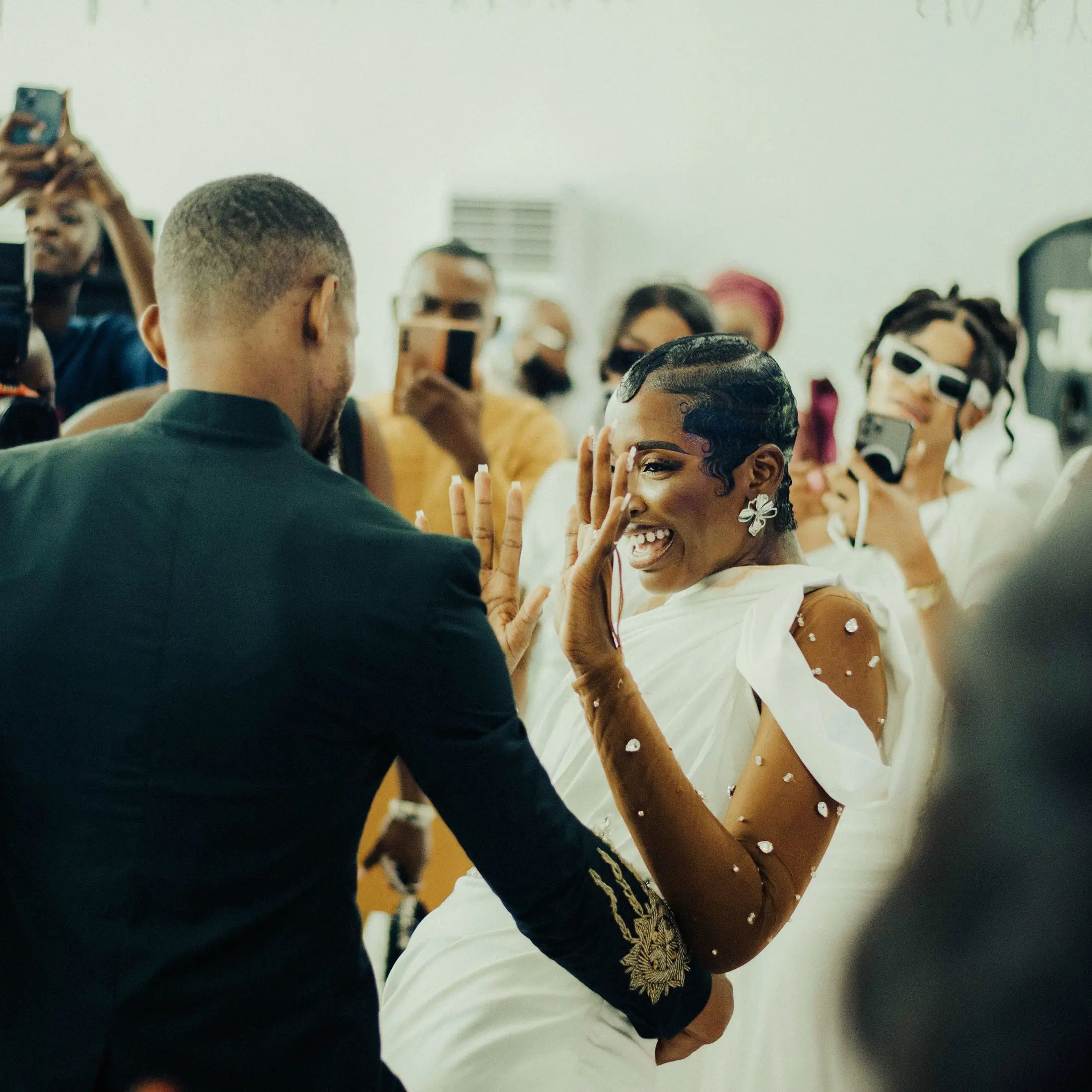 A bride laughing in the first dance as guests film on their phones