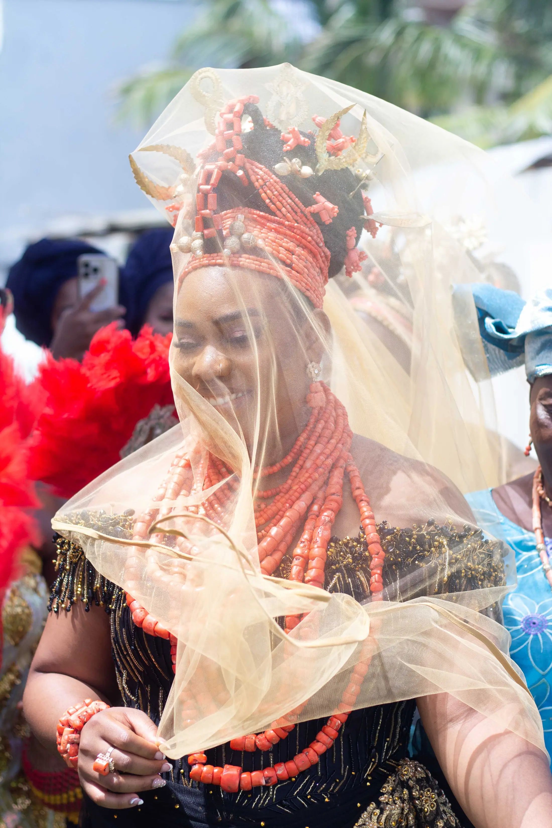 A bride in coral beads and a gold veil at her traditional wedding