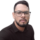 HOMEM MORENO, CABELO PRETO, ÓCULOS PRETO DE GRAU,CAMISA AZUL