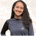 Mulher morena, cabelo cacheado, blusa preta.