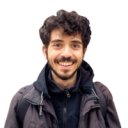 Homem branco barbudo e de cabelo enrolado usando uma blusa de frio