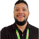 Homem branco de cabelo preto e barba bem feita, camiseta azul