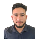 Homem branco de cabelo preto e barba bem feita, camiseta azul