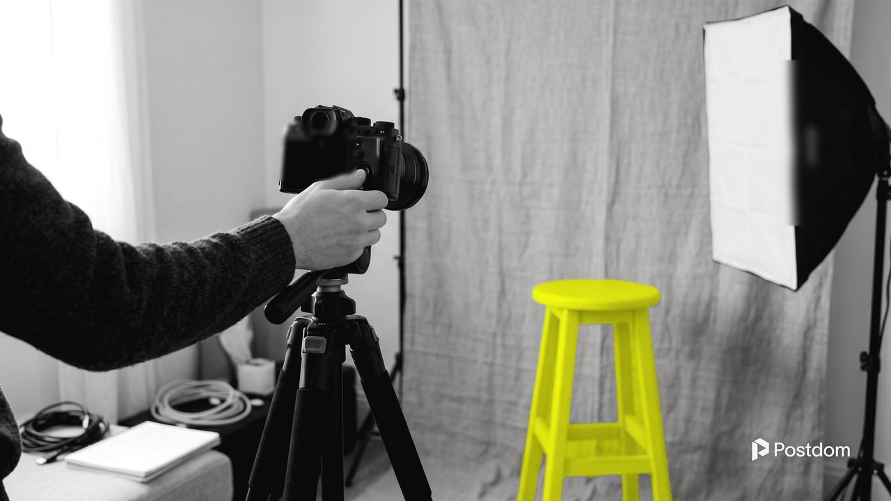 How to make money on YouTube: a creator sets up a camera on a tripod facing a yellow stool in front of a plain backdrop and a softbox light