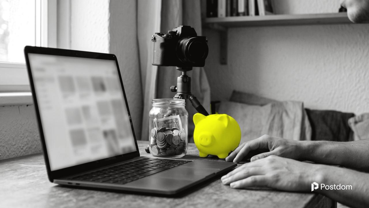 How much does YouTube pay: a creator's desk with a laptop, a camera on a tripod, a jar of coins and a yellow piggy bank