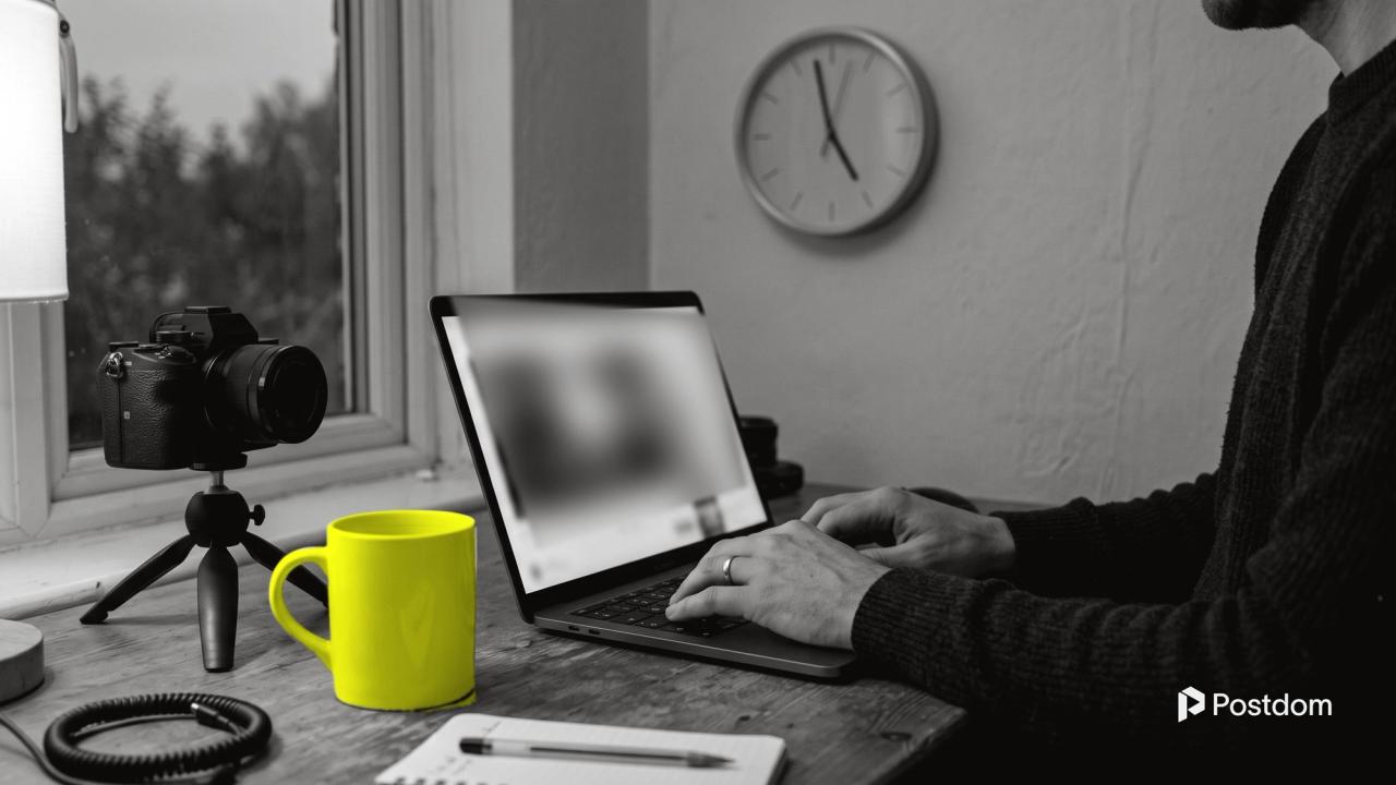Best time to post on YouTube: a creator edits a video on a laptop next to a camera on a small tripod and a yellow mug, a wall clock near five behind