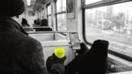 Best time to post on Twitter: a commuter on a morning train holds a phone and a yellow reusable coffee cup by the window