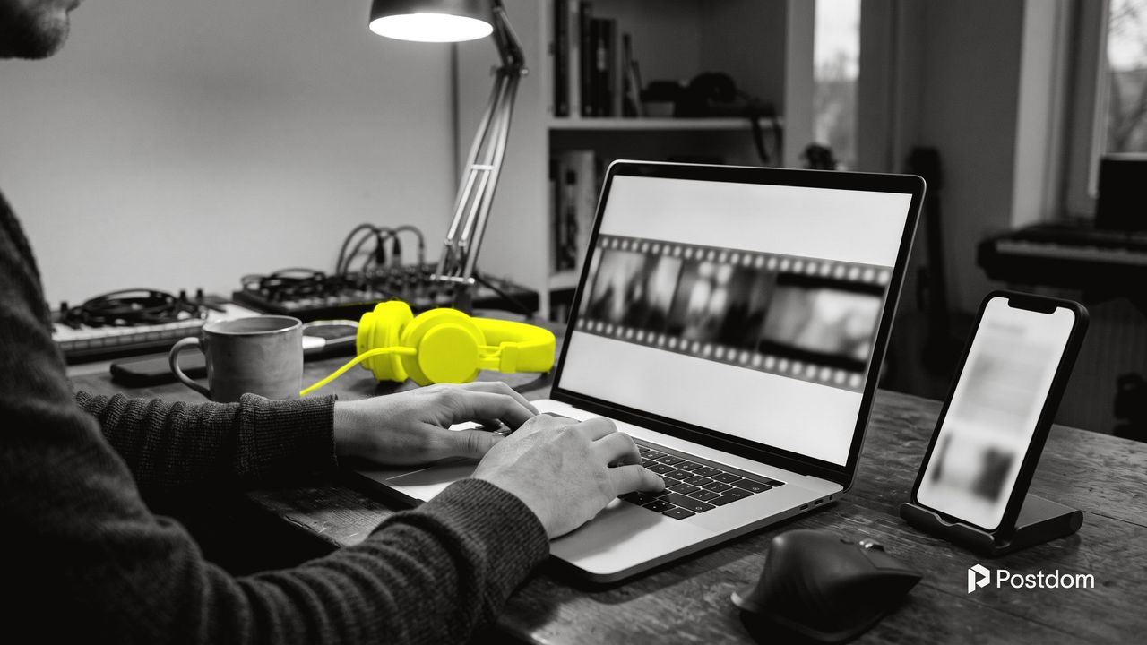Best AI video generators for social media: a creator edits video frames on a laptop beside a phone on a stand and yellow headphones
